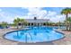 Community pool surrounded by palm trees, lounge chairs, and clubhouse under a sunny sky at 6960 Audobon Osprey Cv, Harmony, FL 34773