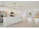 A bright, modern kitchen featuring an island, pendant lighting, white cabinets, stainless appliances and hardwood floors at 701 Marion Oaks Trl, Ocala, FL 34473