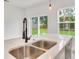 A kitchen island with double sinks, quartz countertops and a backyard view through two windows at 701 Marion Oaks Trl, Ocala, FL 34473
