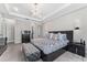 The main bedroom boasts a tufted bench, chandelier, side tables, and access to the ensuite bathroom at 711 Windlass Ct, Kissimmee, FL 34746