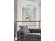 Hallway featuring a modern gray couch with decorative pillows, glass railings, and a stunning crystal chandelier at 711 Windlass Ct, Kissimmee, FL 34746
