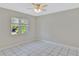 Bright bedroom featuring a ceiling fan, white tile floors, and natural light from a window with blinds at 7709 Pine Hollow Ct, Orlando, FL 32822