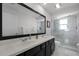Bright bathroom with double sinks, black cabinets, large mirror, and tiled shower at 772 Pickfair Ter, Lake Mary, FL 32746