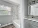 Bright bathroom with white marbled tile, updated vanity, and large window at 1228 Vantage Dr, Orlando, FL 32806
