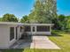 Exterior view of the house with a screened-in porch and a concrete patio on a grassy lot at 1228 Vantage Dr, Orlando, FL 32806