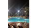 Night view of a sparkling swimming pool, surrounded by palm trees and lounge chairs, inviting relaxation at 12527 Floridays Resort Dr # 603E, Orlando, FL 32821