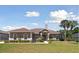 Charming single-story home featuring a stone entrance, manicured lawn, and lush landscaping with palm trees at 564 Dowling Cir, Lady Lake, FL 32159