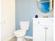 Cozy half-bathroom features new vanity, white fixtures and blue accent wall with decorative mirror at 184 Lake Smart Cir, Winter Haven, FL 33881