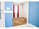 View of the bedroom showcasing neutral carpet, window with red curtains, and blue accent wall at 184 Lake Smart Cir, Winter Haven, FL 33881