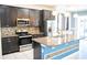 Open kitchen featuring dark wood cabinets, granite countertops, and stainless steel appliances, leading to sliding glass doors at 184 Lake Smart Cir, Winter Haven, FL 33881