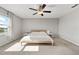 Neutral bedroom with a ceiling fan, bright window, carpet flooring, and simple décor at 5553 Turkey Creek Way, Lakeland, FL 33811