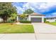 This home features a manicured lawn, mature trees, and a paved driveway leading to a two-car garage at 8023 Canyon Lake Cir, Orlando, FL 32835