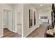 Hallway with wood-look floors, neutral paint, and art leading to a bedroom with carpet at 1076 Clay Blvd, Tavares, FL 32778