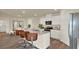 Open kitchen boasts stainless steel appliances, white cabinets, and island with seating, next to a dining area at 1076 Clay Blvd, Tavares, FL 32778
