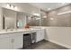 Bathroom with double vanity sinks, large mirrors, white cabinets, and shower with stone tiling at 1103 Silo Dr, St Cloud, FL 34771