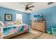 Bright bedroom featuring blue walls, a ceiling fan, and wood floors at 1103 Silo Dr, St Cloud, FL 34771