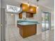 Open kitchen with breakfast bar, wood cabinets, and tile flooring, flowing seamlessly to the outdoor pool area at 1111 Lynx Trl, Winter Springs, FL 32708