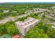 Aerial view of a multi-story condo building, lush greenery, and roads with neighborhood view in the distance at 1150 Carmel Cir # 301, Casselberry, FL 32707