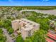 Aerial view showcasing a multi-story condo building surrounded by lush greenery with a lake in the background at 1150 Carmel Cir # 301, Casselberry, FL 32707