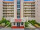 Multi-story condo building featuring balconies, red roof accents, landscaping, and street-facing entry with the address 1150 at 1150 Carmel Cir # 301, Casselberry, FL 32707