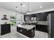 Modern kitchen featuring black cabinets, a granite-topped island, stainless steel appliances, and backyard views at 1558 Terra Verde Way, Ocoee, FL 34761