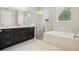 Modern bathroom featuring a large vanity, glass shower, and soaking tub near a window at 15698 Marina Bay Dr, Winter Garden, FL 34787