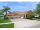 Elegant home featuring a three-car garage, red tile roof, and well-maintained landscaping with a palm tree at 15698 Marina Bay Dr, Winter Garden, FL 34787