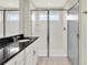 Bright bathroom featuring a glass-enclosed shower and a black countertop with a single sink at 16217 Prairie School Dr, Winter Garden, FL 34787