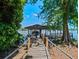 Charming boat dock and covered slip featuring a wooden walkway with rope railings and mature trees at 2001 Bett Mar Ln, Winter Park, FL 32789