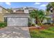 Inviting two-story home with a manicured lawn, palm trees, and a two-car garage at 213 Hideaway Beach Ln, Kissimmee, FL 34746