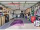 Spacious garage with ample storage cabinets, laundry area, bike and organizational equipment, and a vibrant purple rug at 25307 La Grange Ct, Leesburg, FL 34748