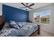 Bedroom featuring navy accent wall, ceiling fan, and a sunny window overlooking well-maintained landscaping at 2900 Sunridge Loop, St Cloud, FL 34771