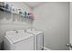 Bright laundry room featuring modern, white appliances and storage shelving at 2900 Sunridge Loop, St Cloud, FL 34771