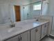 Double sink vanity with gray cabinets, white countertop, large mirror, and glass-enclosed shower at 2980 Embark Trail, St Cloud, FL 34771