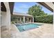 A pristine backyard pool with a covered patio, outdoor fireplace, and lush landscaping offers ultimate relaxation at 4517 Old Carriage Trail, Oviedo, FL 32765