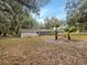 Large backyard featuring mature trees, a fire pit, and a screened-in lanai at 5212 Waterwood Run, Bartow, FL 33830