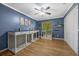 Blue bedroom featuring hardwood floors, ceiling fan, and pet kennels at 5301 Forest Breeze Ct, St Cloud, FL 34771
