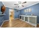 Blue bedroom featuring hardwood floors, ceiling fan, and pet kennels with adjacent dining room at 5301 Forest Breeze Ct, St Cloud, FL 34771