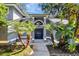 Inviting front entrance with an arched transom window above the double doors, flanked by palm trees and colorful plants at 5301 Forest Breeze Ct, St Cloud, FL 34771