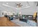 Open-concept living room featuring a large gray sectional sofa, wood floors, and elegant light fixtures at 5648 Cedar Chase Dr, St Cloud, FL 34771