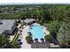 Aerial view of a community pool area with blue umbrellas and lounge chairs surrounded by lush landscaping and trees at 6152 Meriwether, Winter Garden, FL 34787
