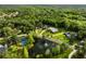 Aerial view of a community with luxury homes, a tennis court, and a pond, surrounded by lush greenery at 8368 Rambling River Dr, Sanford, FL 32771