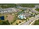 Aerial view of a lakeside community featuring a pool, clubhouse, and tennis courts at 17313 Bracken Fern Ln, Clermont, FL 34714