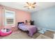 Cozy bedroom featuring a pink and blue painted walls, ceiling fan, window with blinds, and comfortable furniture at 542 Patton Loop, Bartow, FL 33830