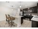 Modern kitchen featuring dark cabinetry, stainless steel appliances, and breakfast bar seating at 542 Patton Loop, Bartow, FL 33830
