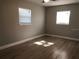Bedroom featuring wood-look floors, neutral walls, two windows, and white trim at 5508 Andora St, Orlando, FL 32807