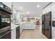 Bright kitchen features stainless appliances, white cabinetry, quartz countertops, and hardwood floors with a seamless open floor plan at 110 Tedworth Ct, Longwood, FL 32779