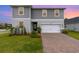 Inviting two-story home with a well-manicured lawn, brick-paved driveway and attached garage at 16448 Winding Preserve Cir, Clermont, FL 34714