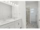 An elegant bathroom boasts a glass shower, double sink vanity, and sleek quartz counters at 16484 Silver Brook Way, Winter Garden, FL 34787
