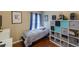 Cozy bedroom featuring hardwood floors, cube storage, and a comfortable bed near window with blue curtains at 16843 Cedar Run Dr, Orlando, FL 32828